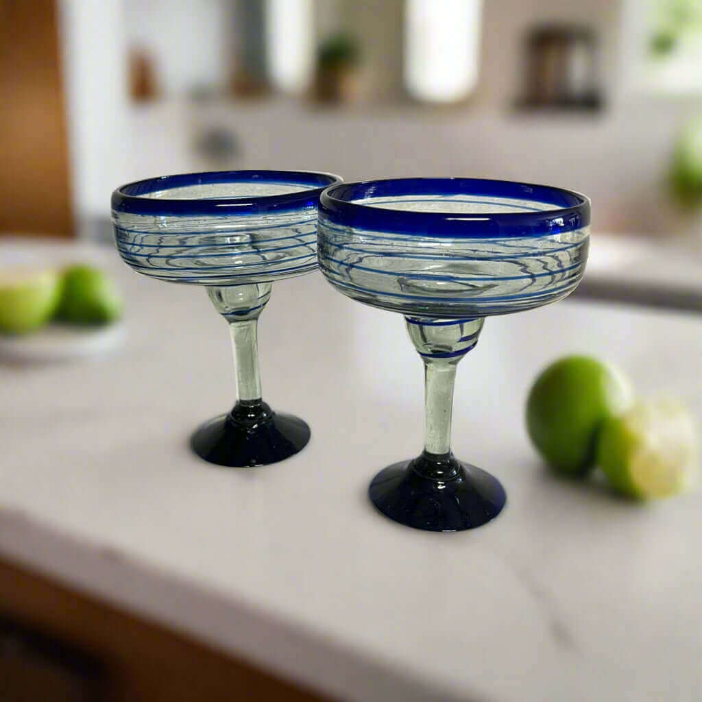 Mexican Margarita Glass | Hand-Blown Blue Swirl Cocktail Cup - pair of hand-blown clear glasses with cobalt blue swirls and rims on kitchen countertop
