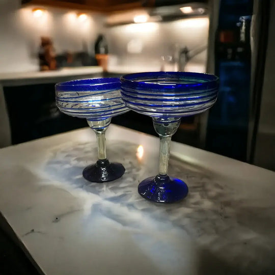 Mexican Margarita Glass | Hand-Blown Blue Swirl Cocktail Cup - pair of hand-blown clear glasses with cobalt blue swirls and wide rims on marble counter