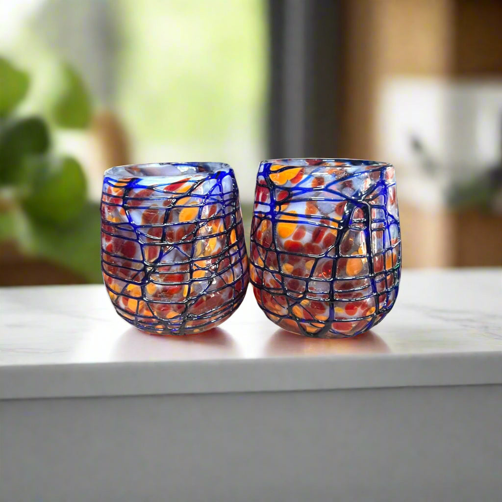 Mexican Stemless Wine Glass | Hand-Blown Orange & Blue Swirl - Pair of hand-blown lead-free glasses with orange and blue swirl pattern on marble