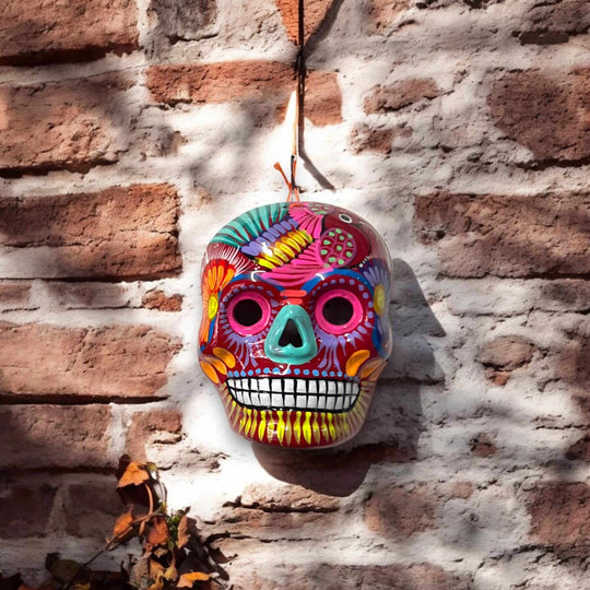 Colorful Calavera Skull | Hand-Painted Mexican Wall Art Decor hanging on brick wall, vibrant hand-painted floral details