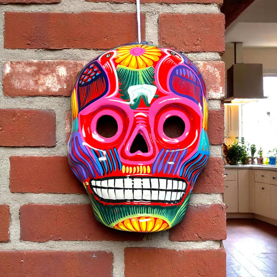 Colorful Calavera Skull | Hand-Painted Mexican Wall Art Decor - vibrant hand-painted Talavera skull with floral motifs hanging on brick wall