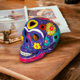 Guerrero Calavera Skull | Large Hand-Painted Day of the Dead Art - vibrant hand-painted purple ceramic skull with floral motifs on wooden table