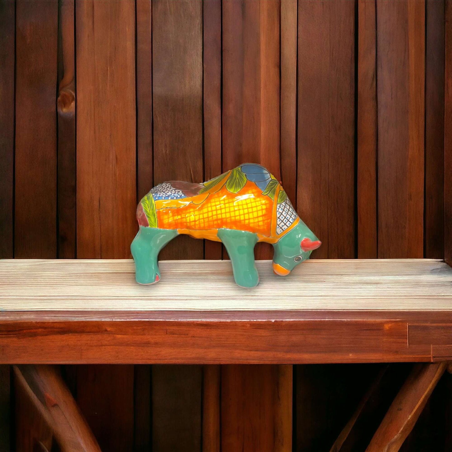 Talavera Bull Statue | Hand-Painted Mexican Ceramic Animal Decor - hand-painted orange green floral ceramic bull on wooden shelf
