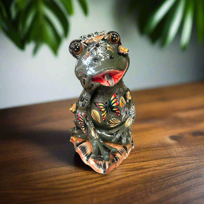 Hand-Painted Talavera Frog Statue | Mexican Ceramic Animal Decor - jet-black hand-painted frog with colorful floral and butterfly details on wooden surface