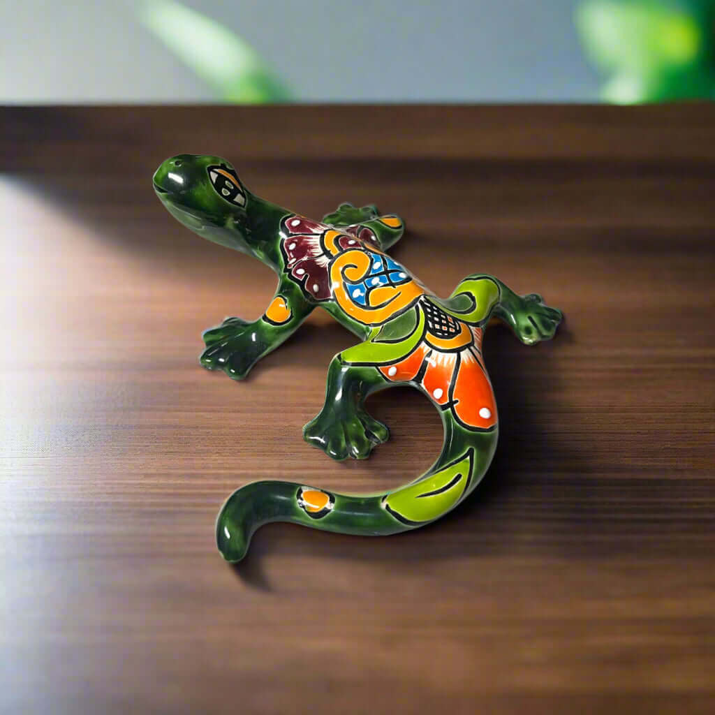 Talavera Lizard Figurine | Hand-Painted Mexican Ceramic Sculpture on wooden table, vibrant hand-painted floral and geometric patterns, green and orange ceramic lizard