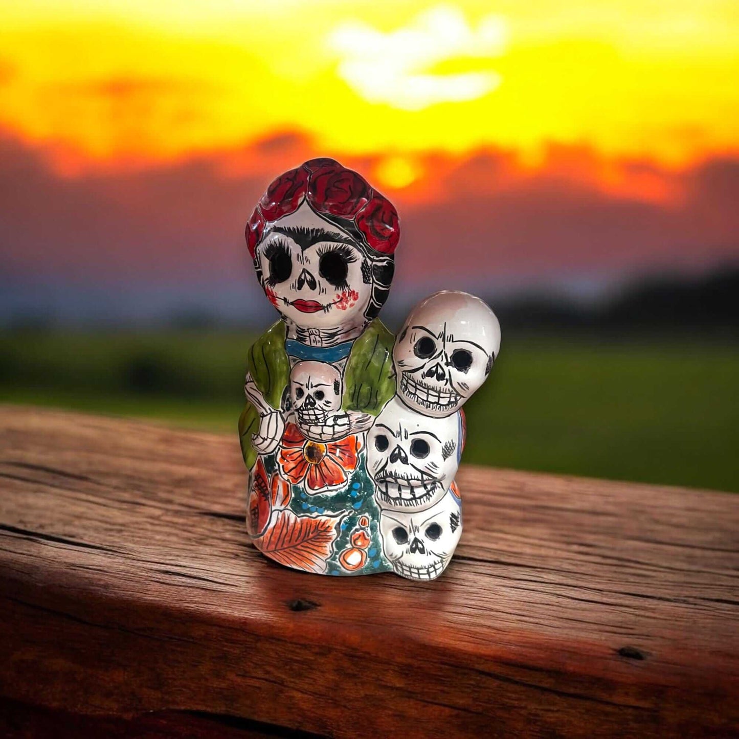 Handcrafted Talavera Frida Statue | Colorful Day of the Dead Calavera Skull Decor on wooden table with sunset background, hand-painted Talavera skull figurine