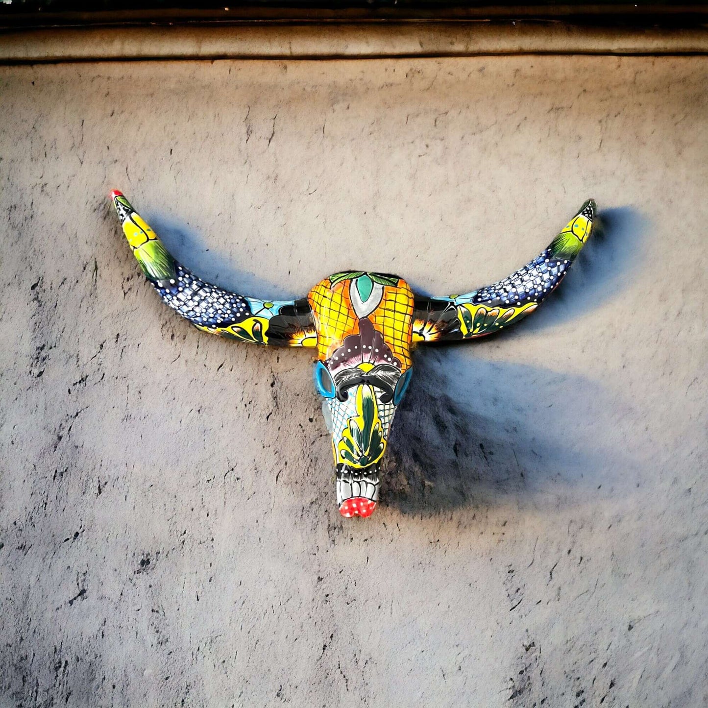 Talavera Longhorn Wall Decor | Handcrafted Mexican Bull Skull Art — colorful hand-painted Talavera skull with long horns on adobe wall