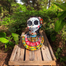 Vibrant Talavera Skeleton Woman Statue | Handcrafted Day of the Dead Decor on wooden pallet surrounded by greenery, hand-painted Mexican Talavera bust