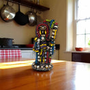 Handmade Aztec Warrior Statue | Colorful Grim Reaper Figurine handcrafted Talavera-style beaded sculpture on wooden table in sunlit kitchen