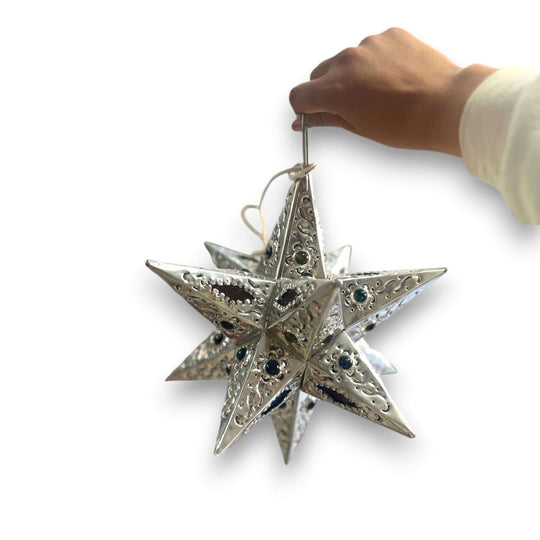 Hand holding a silver Handmade Metal Star Ornament | Stained Glass Light Fixture with punched metal and decorative glass accents