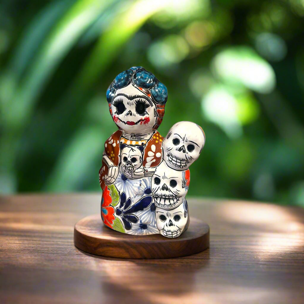 Handcrafted Talavera Frida Statue | Colorful Day of the Dead Calavera Skull Decor — hand-painted Mexican Talavera Frida with stacked skulls on wooden base
