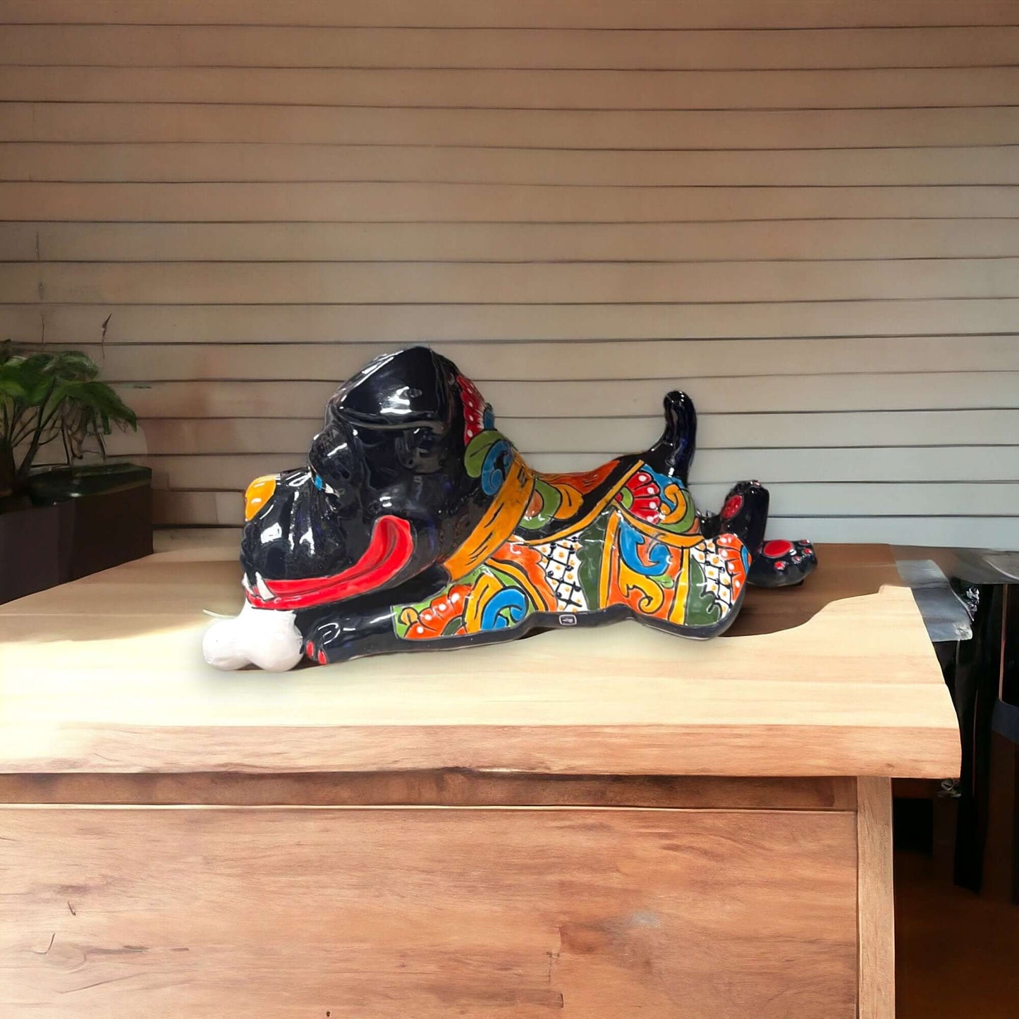 Handpainted Talavera Ceramic Large Laying Dog Decor with Bone displayed on wooden table, colorful hand-painted Mexican Talavera design