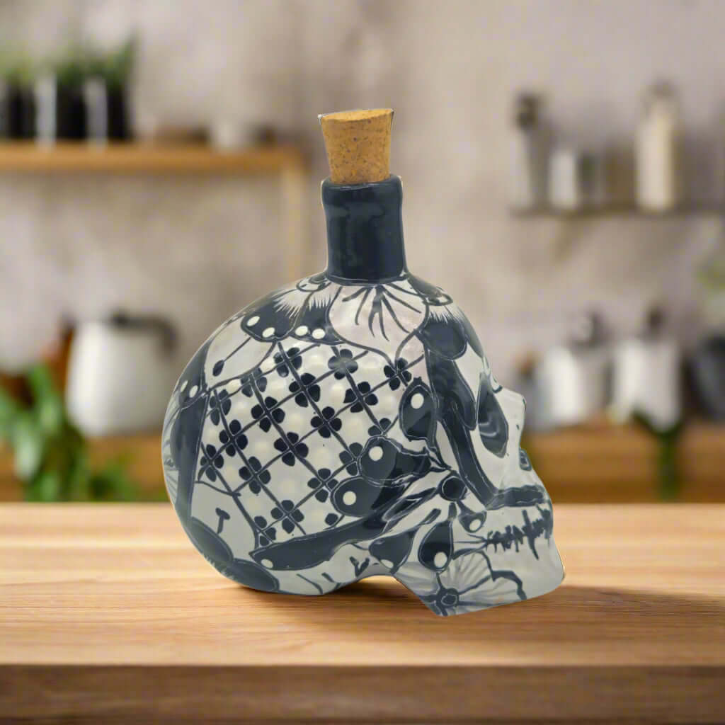 Talavera Skull Decanter with 6 Shot Glasses | Mexican Bar Set - hand-painted black and white Day of the Dead skull decanter on wooden counter