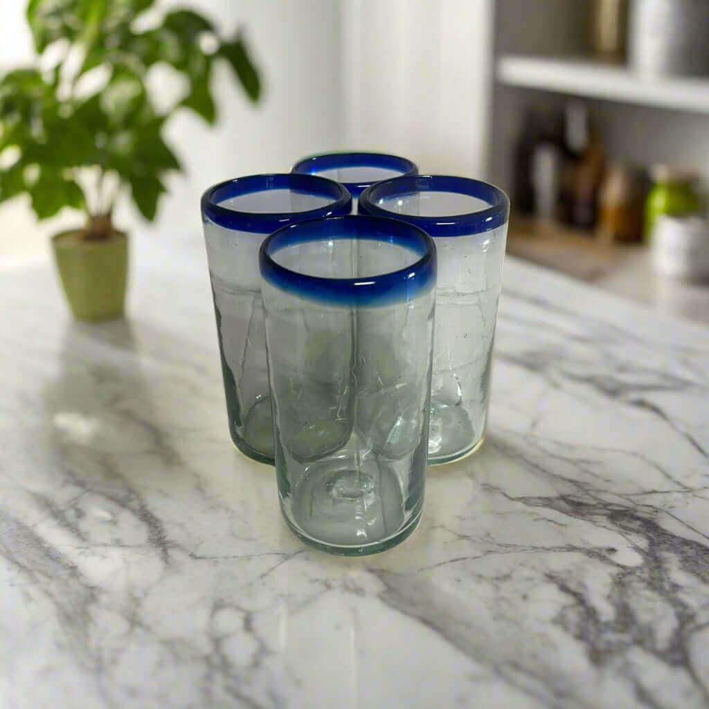 Mexican Blue Rim Tumbler | Hand-Blown Clear Glassware - set of four hand-blown clear glasses with cobalt blue rims on marble countertop