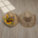 The Talavera Hub two tan cowboy hats, one with sunflowers, the other with etched bull skull and horseshoes.
