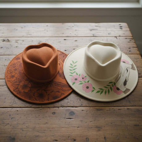 The Talavera Hub Mexican Suede Sombrero with heart crown, one tan with floral burn design, one cream with floral & horse design.