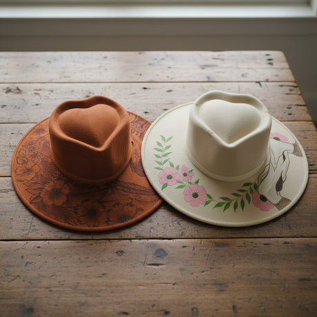 The Talavera Hub Mexican Suede Sombrero with heart crown, one tan with floral burn design, one cream with floral & horse design.