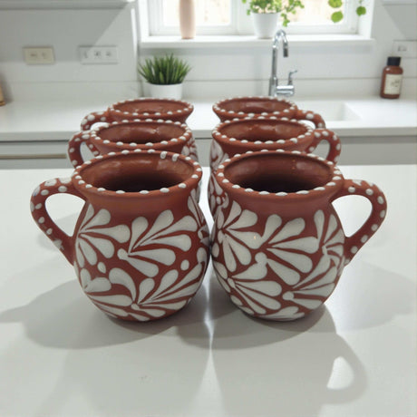 Set of 50 Talavera Jarritos | Handcrafted Mexican Clay Mugs - hand-painted white floral clay mugs arranged on kitchen counter, kiln-fired lead-free glaze