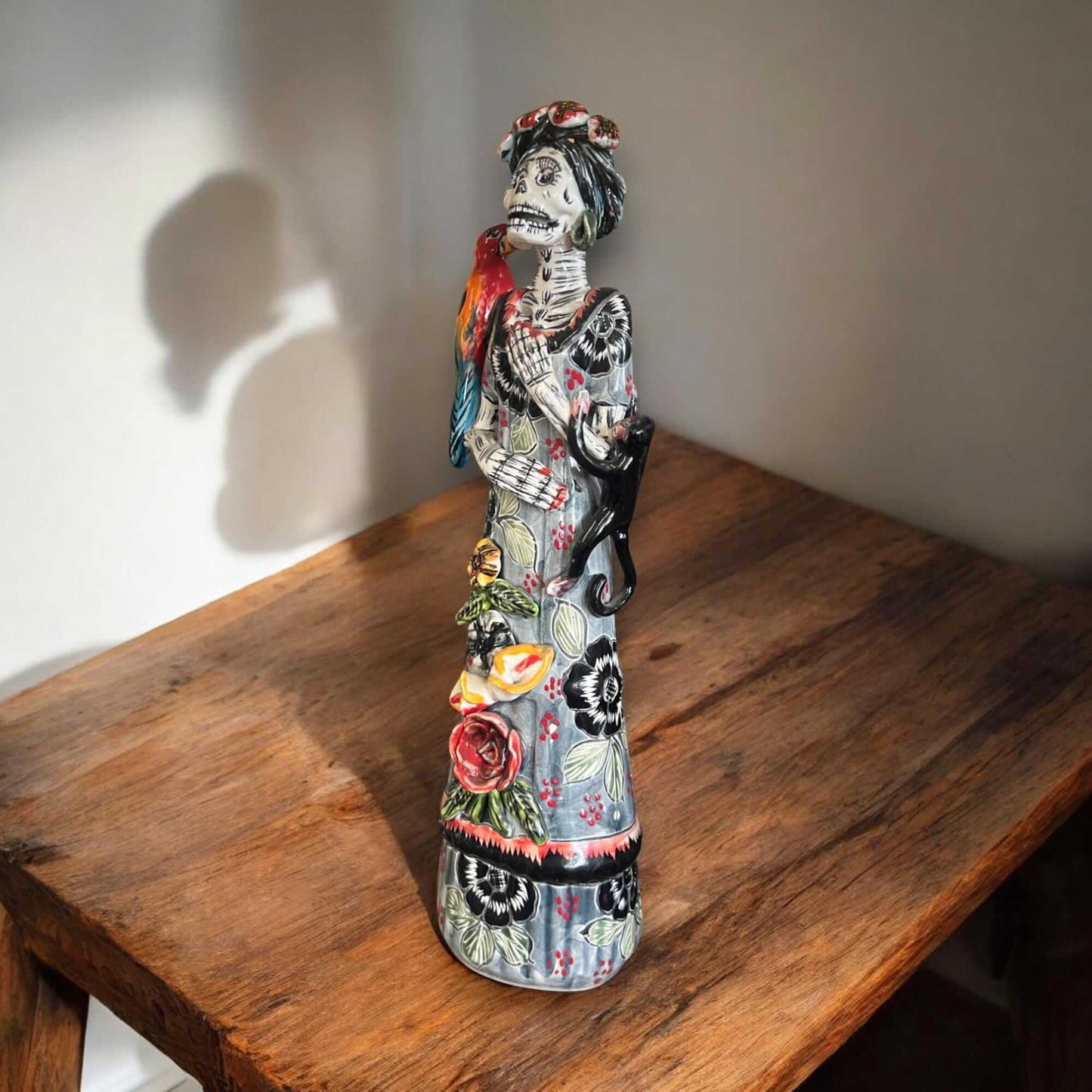 Talavera Catrina Figurine | Day of the Dead Skeleton with Monkey & Bird hand-painted Talavera Catrina on wooden table with parrot and monkey accents