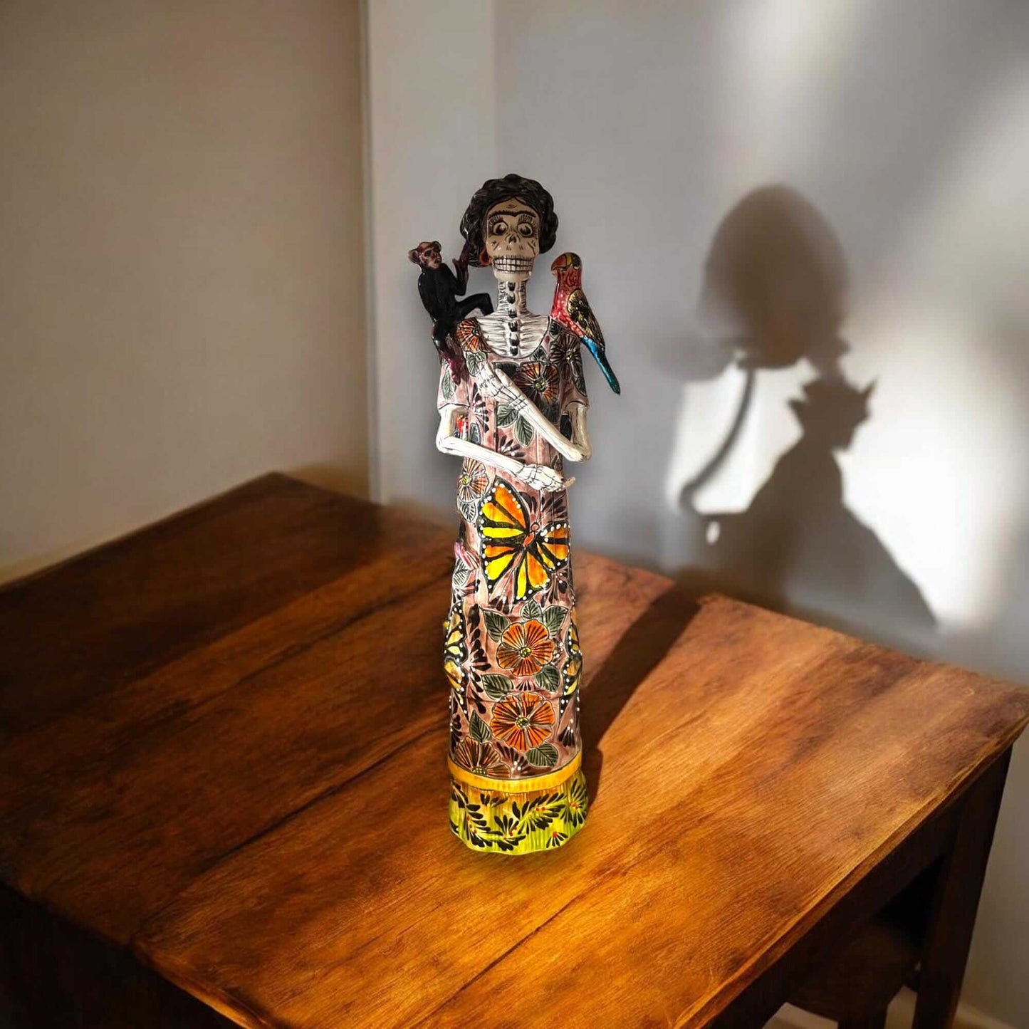 Talavera Catrina Figurine | Day of the Dead Skeleton with Monkey & Bird hand-painted Talavera Catrina on wooden table with parrots and monkey