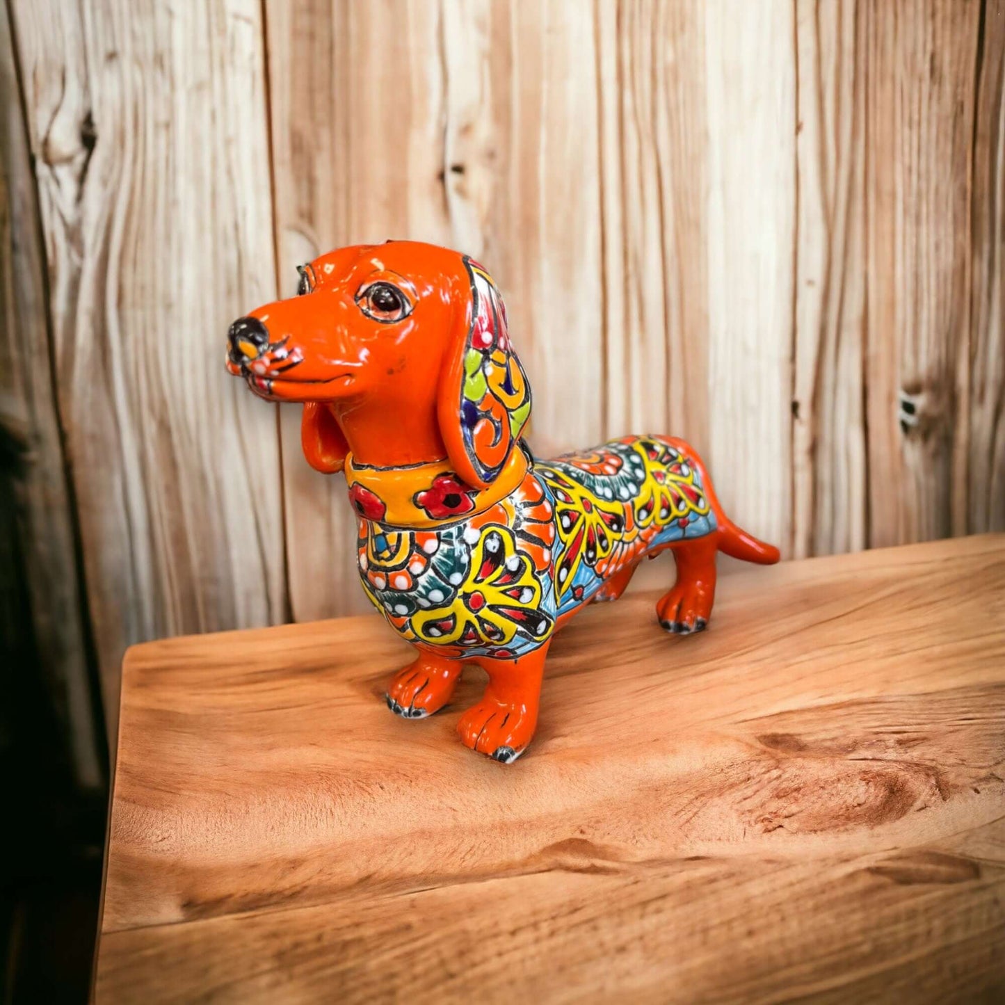 Talavera Dachshund Statue | Colorful Hand-Painted Dog Figurine - orange hand-painted Talavera dachshund with floral patterns on wooden table