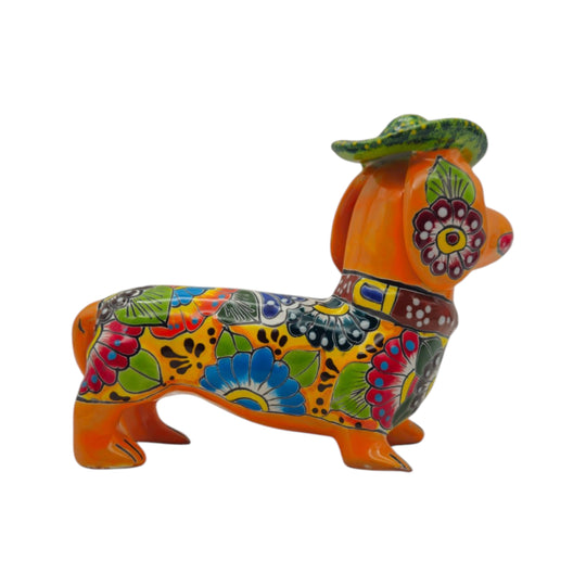 Side view of an orange Talavera dachshund statue with colorful floral patterns