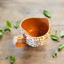 Talavera Heart Mug | Hand-Painted Mexican Coffee Cup showing heart-shaped, hand-painted orange ceramic mug with white floral design and swirled handle