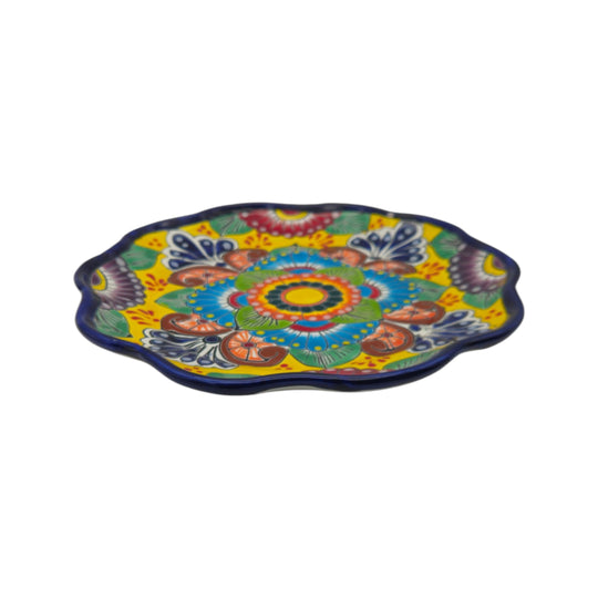 Side view showing the scalloped edge and colorful floral design of a yellow Talavera plate