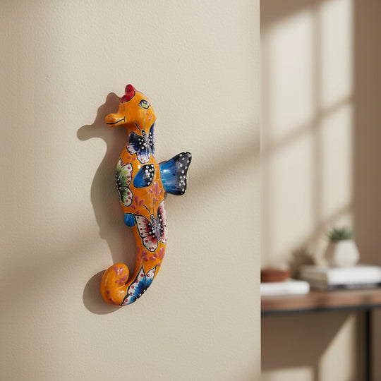 The Talavera Hub orange ceramic seahorse figurine with hand-painted butterflies and floral motifs in blue, pink, and green.