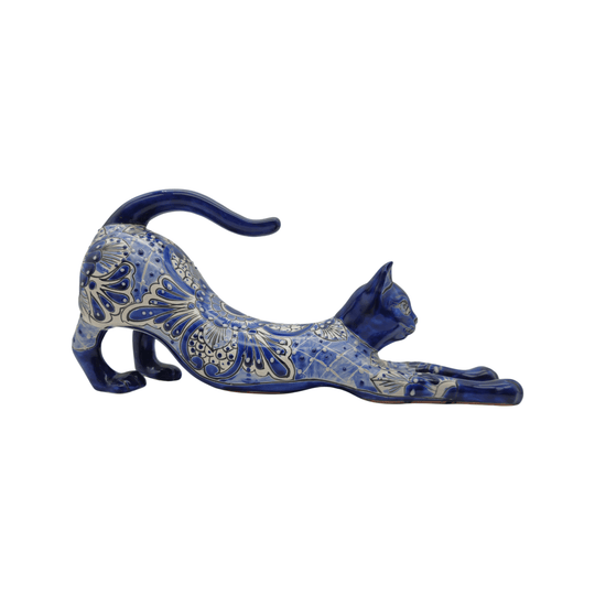 Side view of a blue and white Talavera cat statue in a stretching pose