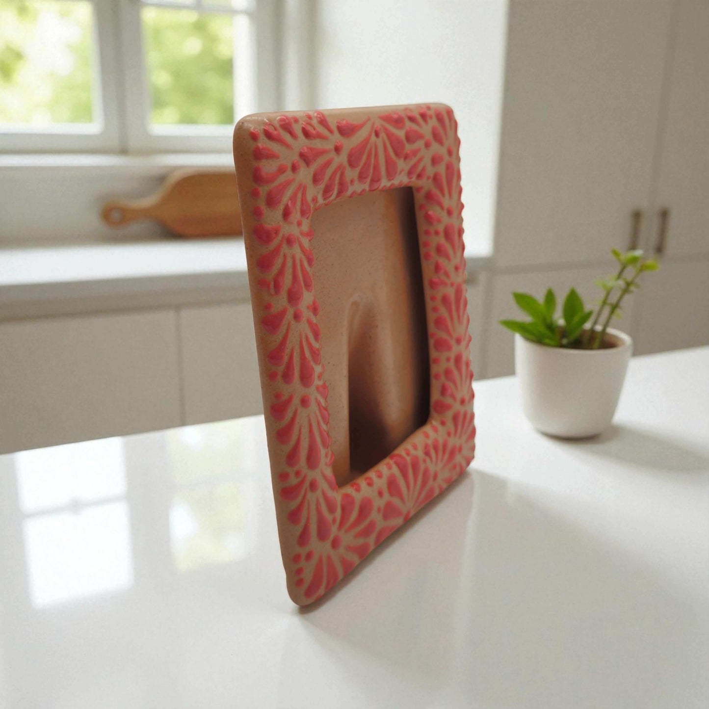 Talavera Terracotta Photo Frame | Pink Floral Accent hand-painted terracotta photo frame with pink floral motifs on a kitchen counter