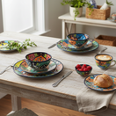 The Talavera Hub 43-piece dinnerware set with vibrant floral patterns in blue, orange, green, and yellow. Hand-painted ceramic.
