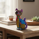 The Talavera Hub hand-painted ceramic sitting cat statue with vibrant Mexican folk-art patterns on a wooden table.