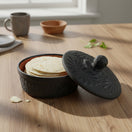 The Talavera Hub black ceramic tortilla keeper with carved floral motifs and a matte finish. Handcrafted in Mexico.