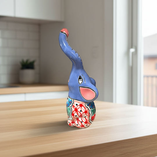 The Talavera Hub blue ceramic elephant statue with colorful hand-painted floral patterns and a pink trunk.