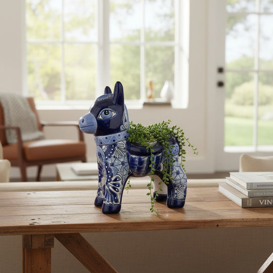 The Talavera Hub blue and white handmade Mexican pottery donkey planter with intricate floral patterns on a wooden table.