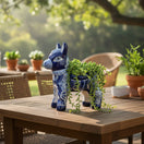 The Talavera Hub handmade blue and white donkey planter with intricate floral patterns holding a trailing succulent.