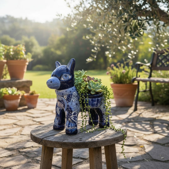 The Talavera Hub handmade blue and white ceramic donkey planter with intricate floral patterns on a wooden stool.