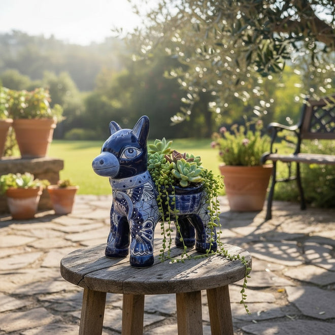 The Talavera Hub handmade blue and white ceramic donkey planter with intricate floral patterns on a wooden stool.