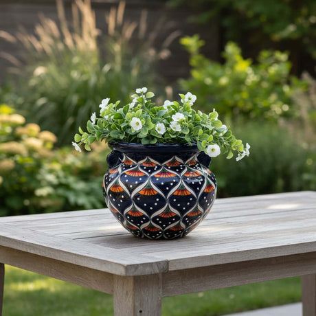 The Talavera Hub hand-painted ceramic pot with peacock motifs in blue, orange, green, and white. Features handles and glossy finish.