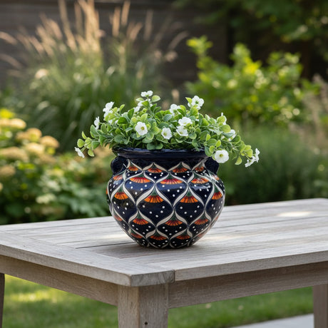 The Talavera Hub hand-painted ceramic pot with peacock motifs in blue, orange, green, and white. Features handles and glossy finish.