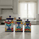The Talavera Hub 3-piece blue rim ceramic canister set with vibrant hand-painted floral patterns on a marble kitchen counter