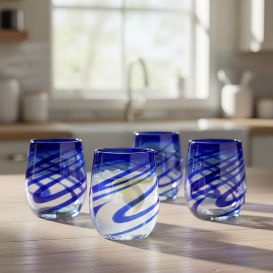 The Talavera Hub hand-blown stemless wine glasses with blue swirls, made from recycled glass.