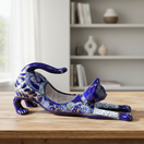 The Talavera Hub hand-painted blue Talavera cat planter with white floral details, stretching pose.
