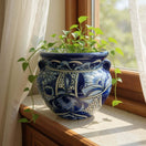 The Talavera Hub handmade blue and white ceramic planter with intricate floral patterns sitting on a sunny windowsill.