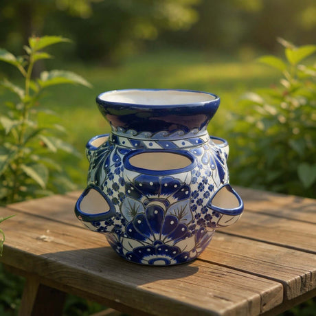 The Talavera Hub handmade ceramic strawberry planter with blue and white floral patterns on a wooden garden table.
