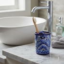 The Talavera Hub hand-painted blue and white ceramic toothbrush holder with floral motifs on a marble bathroom vanity.