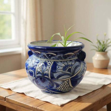The Talavera Hub handmade blue and white floral Talavera planter with a cobalt rim on a wooden table.