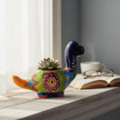 The Talavera Hub handcrafted Brachiosaurus ceramic planter with vibrant floral patterns and a small succulent.