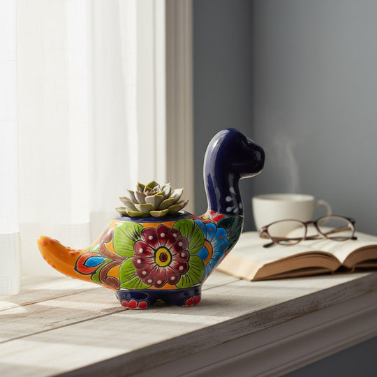 The Talavera Hub handcrafted Brachiosaurus ceramic planter with vibrant floral patterns and a small succulent.